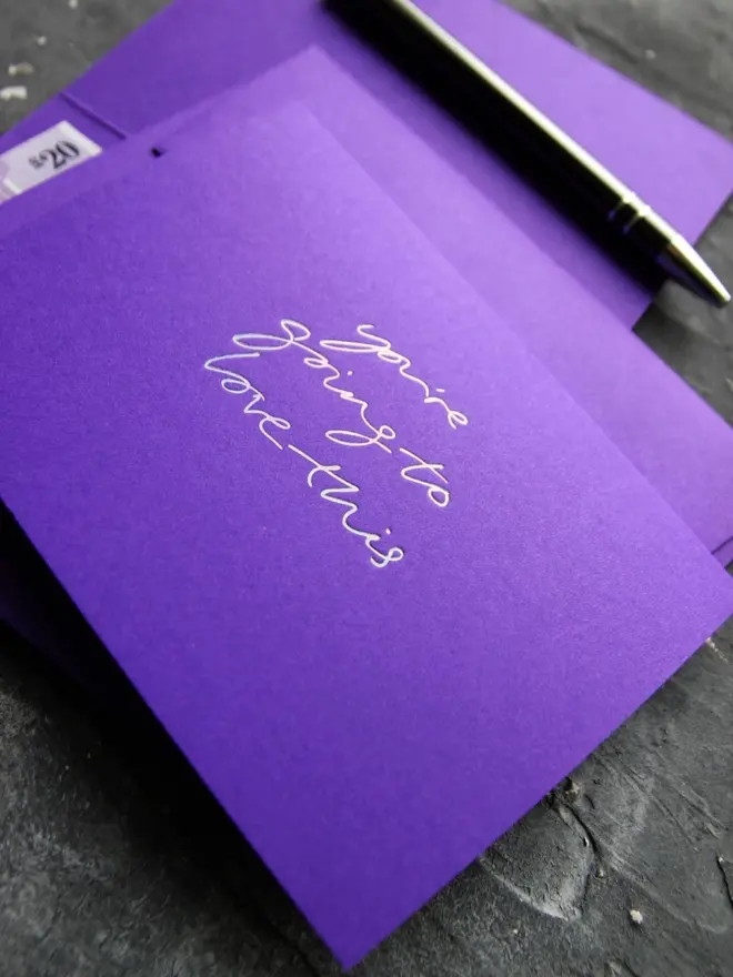 Hand foiled cash card or money wallet in a royal purple colour handfoiled in shiny holographic foil text which says ‘you’re going to love this’.