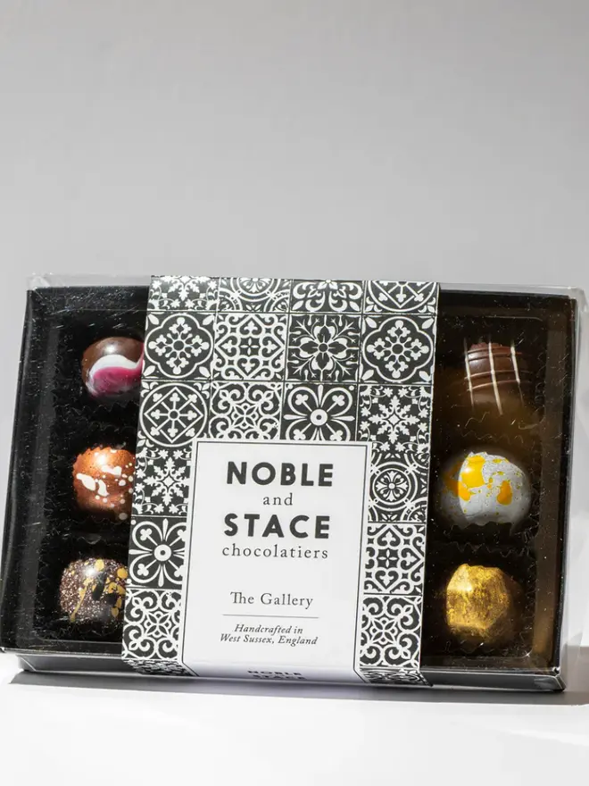 The original gallery chocolates in a black box on a white table, pack of 12. 