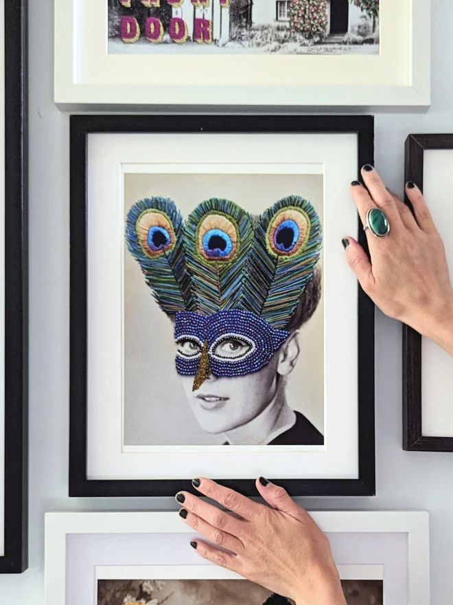 Woman wearing embroidered peacock mask print held in frame on wall 