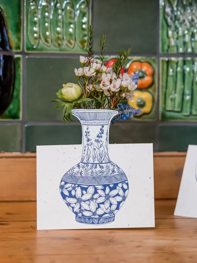 Ruby & Bo Plantable Dahlia Card on a white plinth amongst garniture of porcelain vases