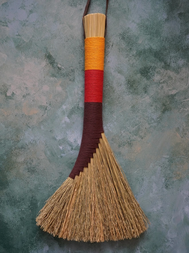 Broomcorn handbroom with brown, red and gold hemp cord binding