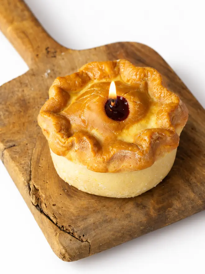 hand raised pork pie candle on a wooden board. 