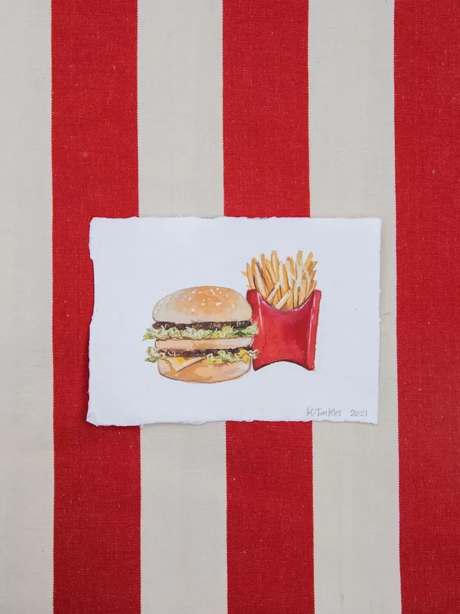 Katie Tinkler Burger and Chips seen on a striped background.