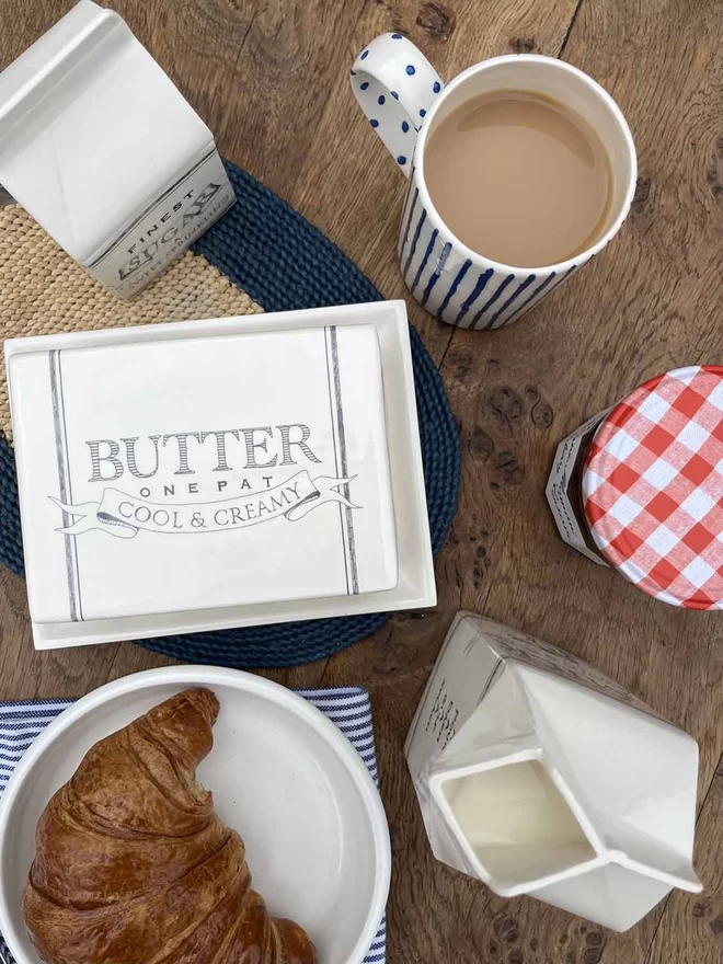 Above view of matching handmade ceramics butter dish , sugar pot and milk carton.