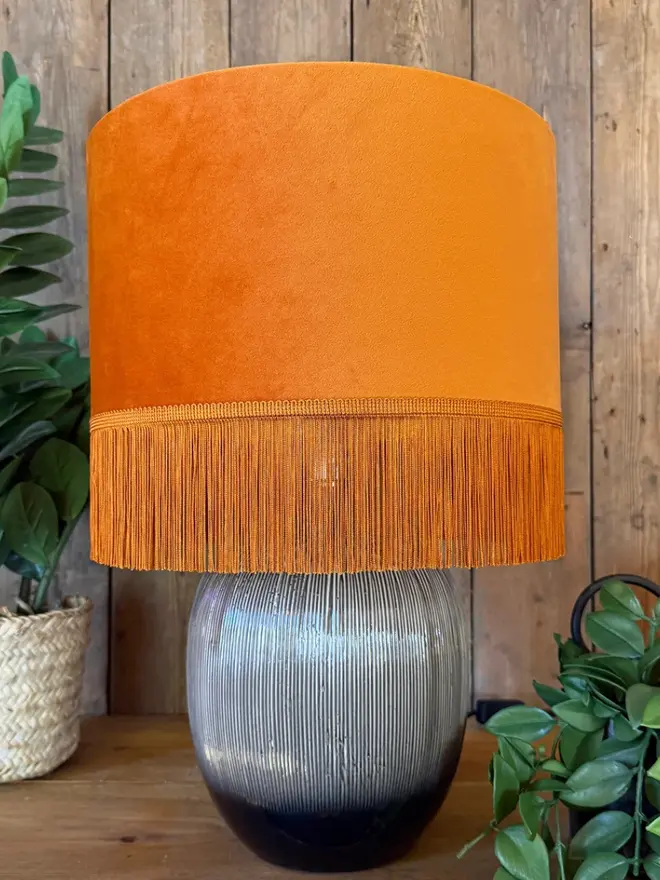 Rust Orange Velvet Lampshade With Gold Lining & Fringing, on a table. 