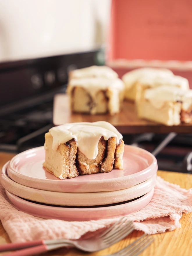 Cinnamon Bun on a stack of pink plates with a gift box in the background