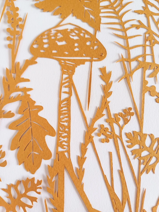 Closeup of papercut detail from Autumn themed personalised letter papercut.  Raw sienna papercut including oak leaf, toadstool and ferns