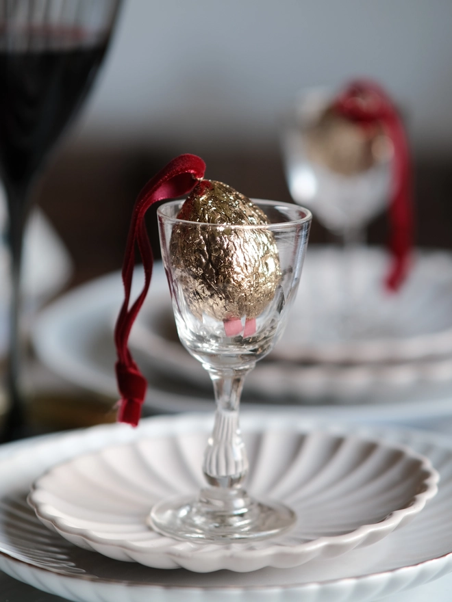Handmade walnut Christmas ornament with delicate gold gilding, showing the natural shape and grain of the wood. A traditional, nostalgic Christmas tree decoration with timeless old-fashioned charm.