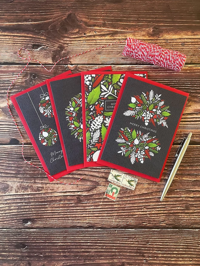Set of 4 Christmas Cards with Red, White, and Green Pressed Winter Leaf Designs - Red Envelopes - Wooden Tabletop - Twine, Vintage Stamps, Silver Parker Pen