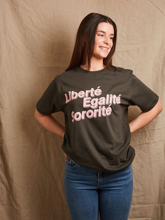 Model is wearing a charcoal grey cotton t-shirt with the slogan Liberté, Egalité, Sororité in pale pink written on the front