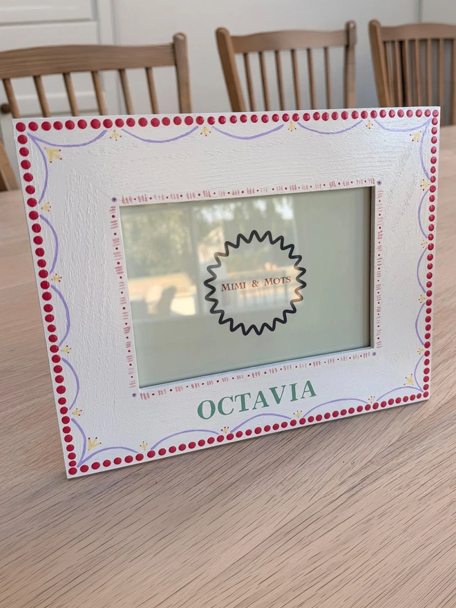 Girls’ Personalised Hand Painted White Photo Frame. A photo frame with intricate pink, white, purple and yellow designs.