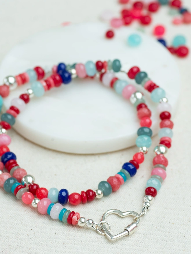 Add instant colour to your jewellery collection with the Love Drunk Necklace. Crafted with coral red jade, aqua agate and gold plated beads, this heart carabiner necklace is playful, bold and beautifully wearable. A vibrant beaded necklace designed to celebrate individuality, confidence and sunny, feel-good style.