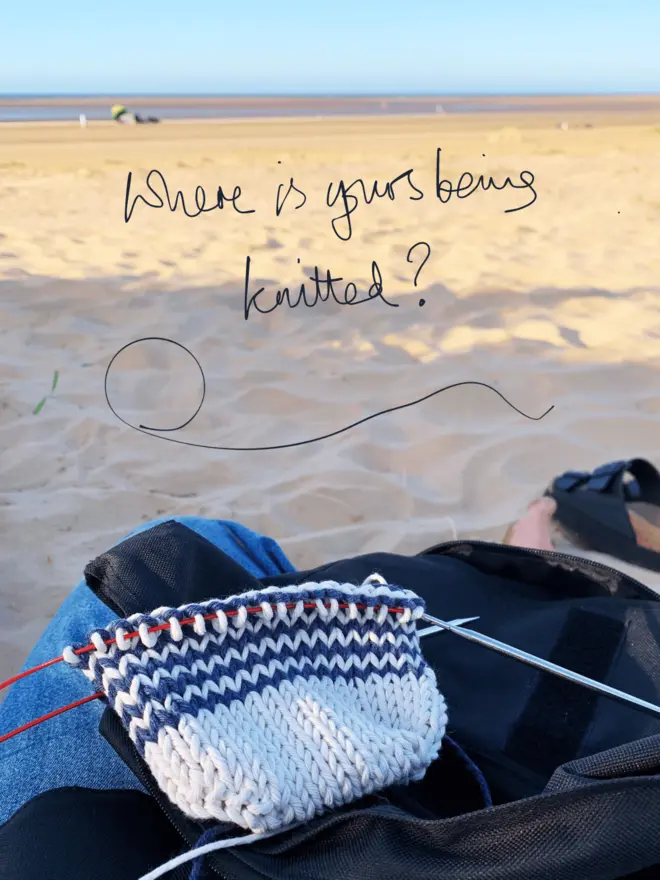 Polly sitting on a beach knitting with the caption "where is yours being knitted?"