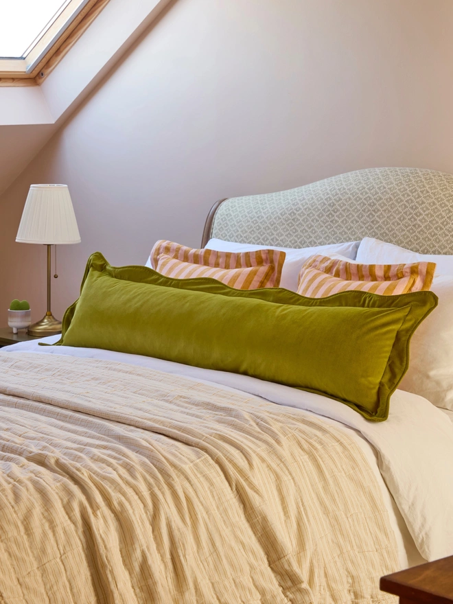 Handmade peach and mustard stripe linen oxford cushion styled with velvet bolster cushion on bed, Kika Bespoke