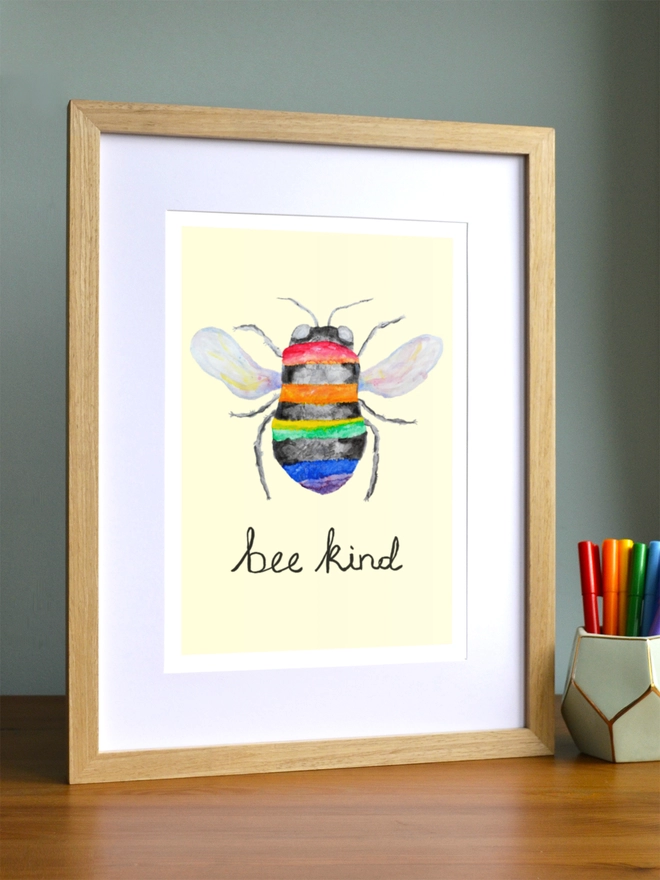 Art print saying 'Bee kind' in a brown frame in a child's room