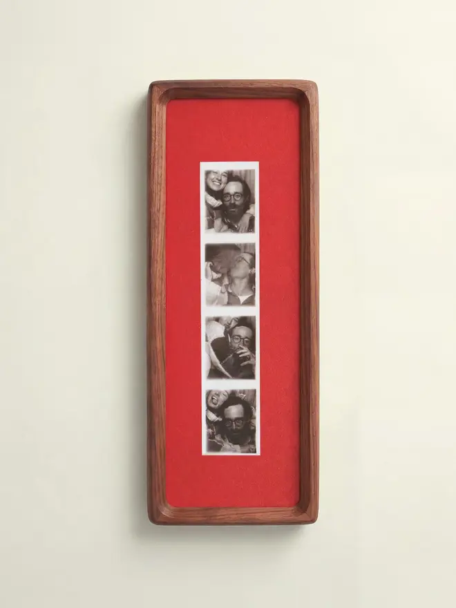 Mounted Photobooth Solid Wood Frame, with red background, hanging on a white wall. 