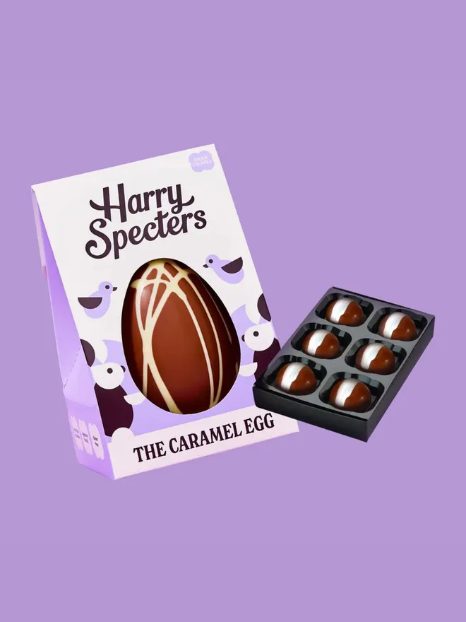 A caramel chocolate Easter egg with white chocolate swirl, next to a small box of luxury chocolates