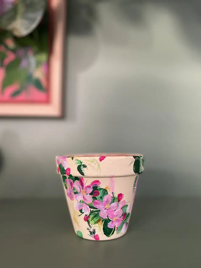 hand painted terrecotta floral plant pot background in a pale yellow with pink and white blossom flowers