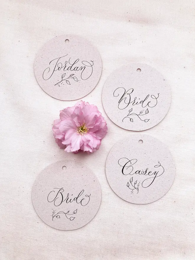 circular calligraphy wedding place cards. white circular place card with black calligraphy.
