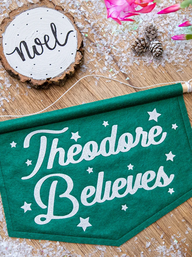 personalised "believe" christmas banner in holly green felt with white glitter text.