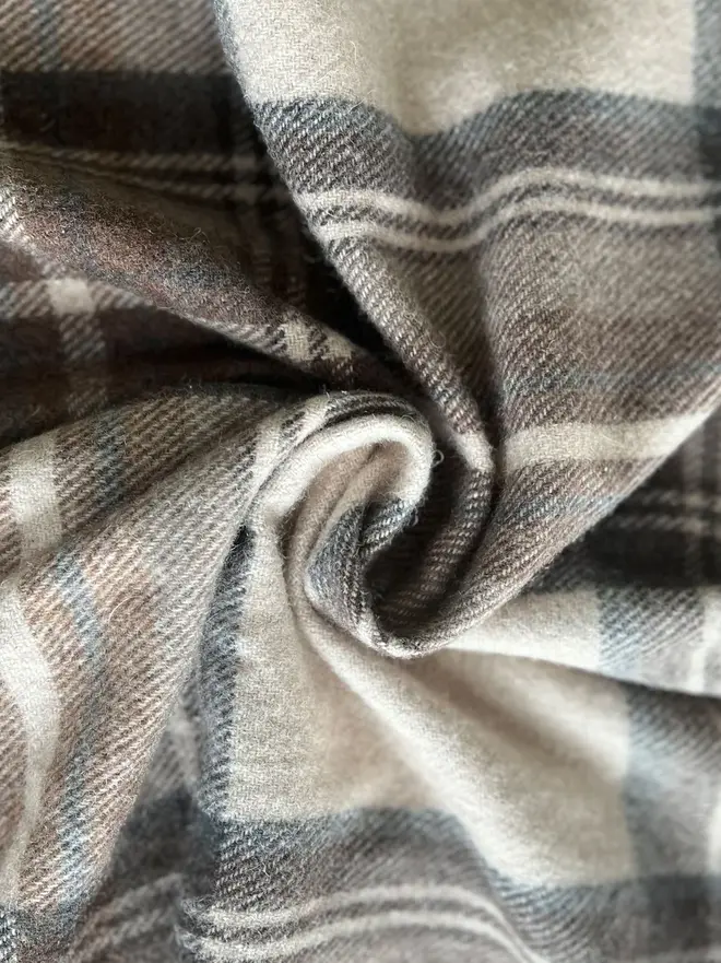 Stewart Natural Dress Blanket, a brown blanket curled up. 