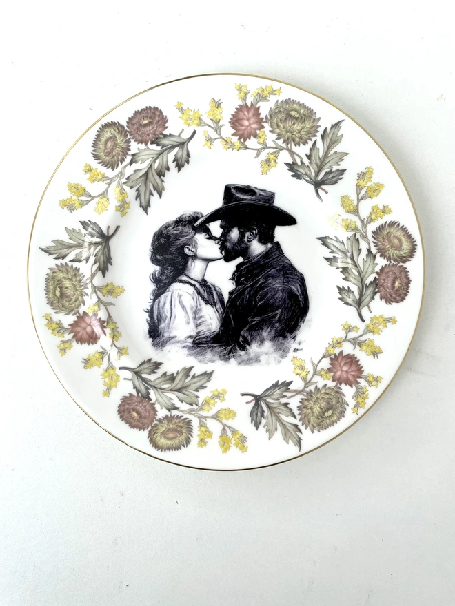 a vintage plate with dark blue and white border has a black and white vintage illustration of a cowboy on horseback in the centre