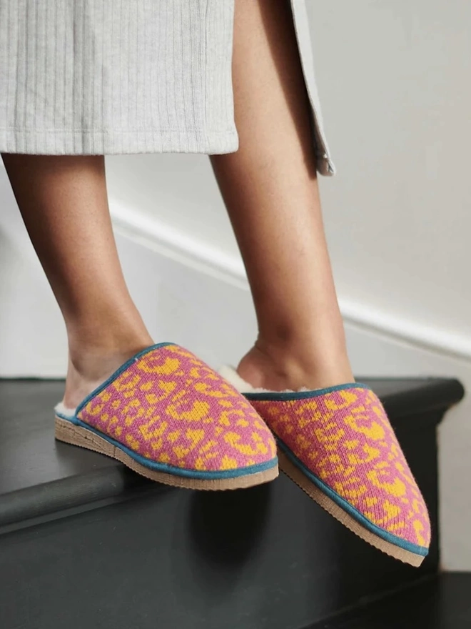Women's Lambswool & Sheepskin Slippers, a person wearing a pair of colourful slippers indoors. 