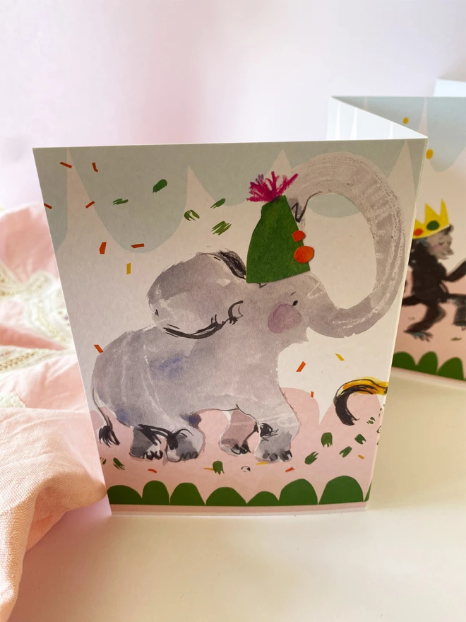 Party Animals illustrated concertina card by Esther Kent  shows elephant in party hat against pink cloth