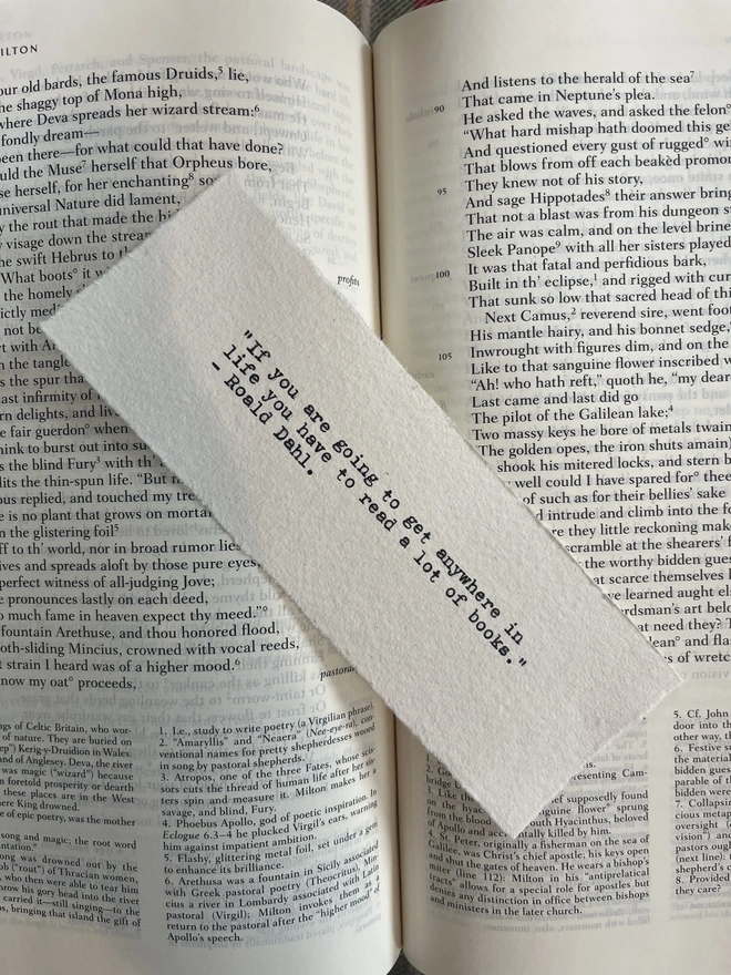 A handmade cotton rag paper bookmark with deckled edges, featuring a custom quote typed in black ink with a vintage antique typewriter.