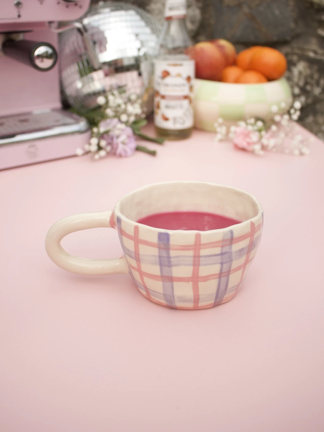 pink and purple gingham striped patterned stoneware pottery mug with bright pink drink inside