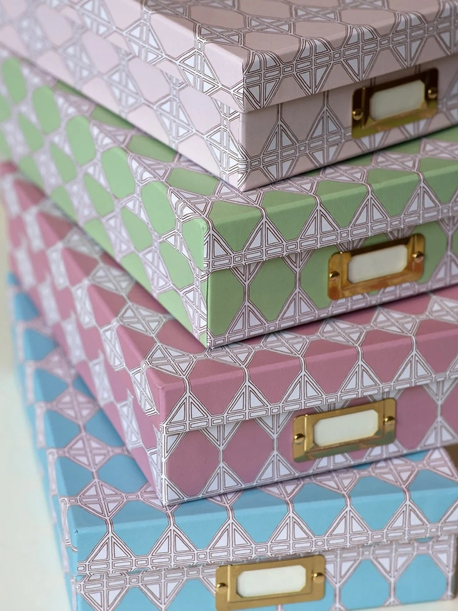 Tijan Lidded Portfolio Box, a collection of colourful portfolio boxes stacked on a plain surface. 