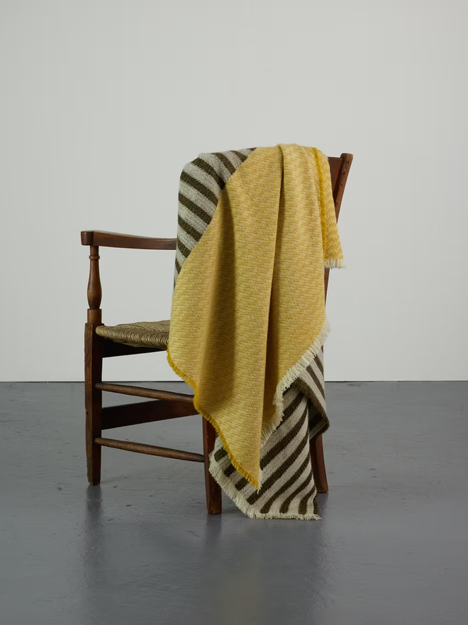 hiolair lambswool blanket. a yellow and brown striped blanket photographed thrown over a chair.