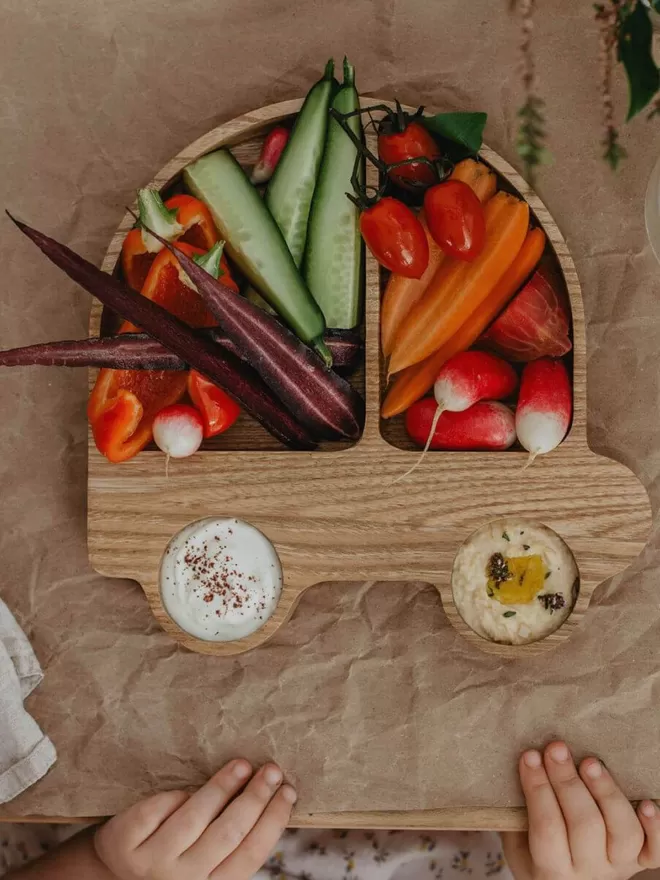 Eco wooden car plate with veggies in the plate and dip in the wheels birds eye view