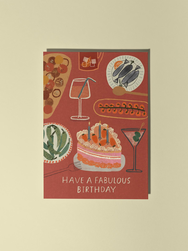 foodie illustrated birthday card. brick red card illustrated with food items including a heart shaped cake, cocktails and tapas.