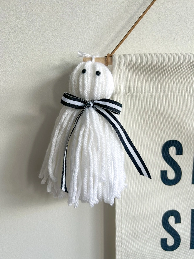 Tassel ghosts on a spooky Season Halloween Banner with tassel ghosts and a black trim