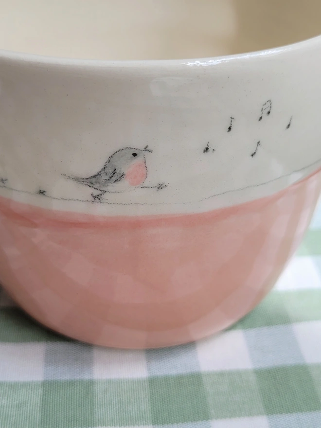 pink ceramic pottery tumbler with pink robin bird  on a green gingham tablecloth