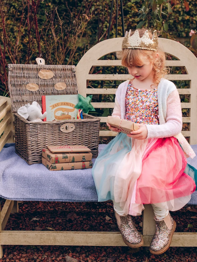 child sat on bench with christmas eve wicker hamper basket