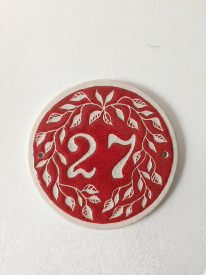 Custom Round Ceramic House Number with Leaves. A house number in red.