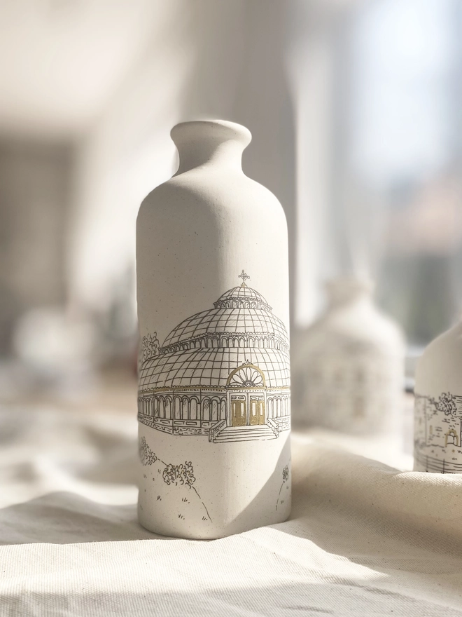 Ceramic vase with black hand drawn venue illustration featuring metallic gold highlights 