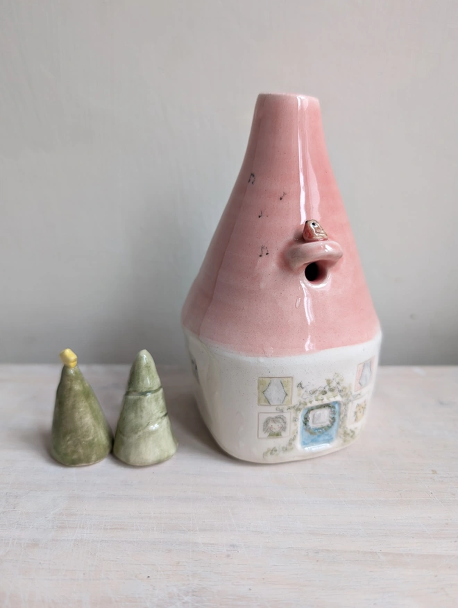 bud vase in the shape of a house with a red robin and tiny windows and door with a pink roof and cat and lady looking out of the window