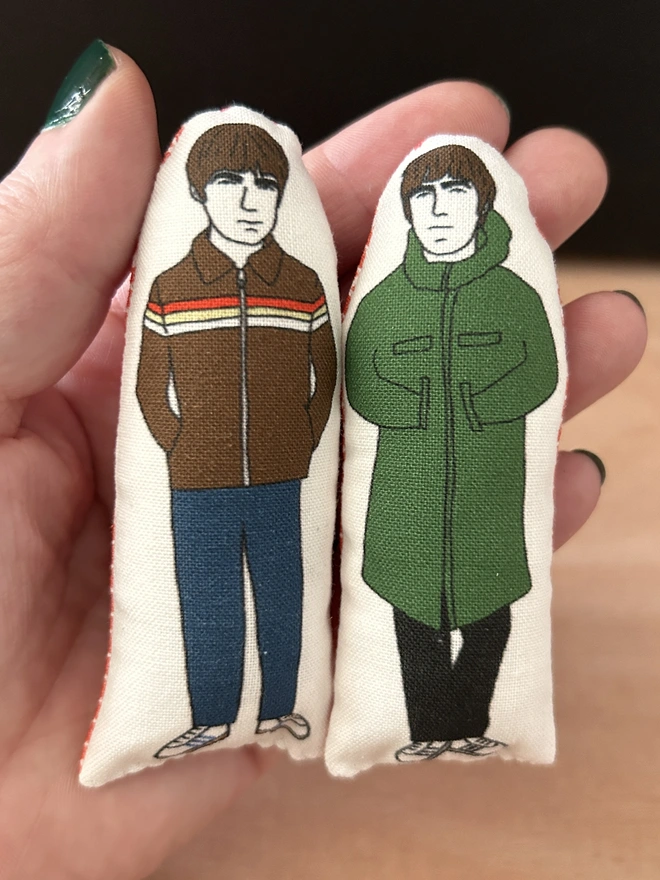 Mini illustrated fabric dolls of Oasis brothers Noel and Liam Gallagher.