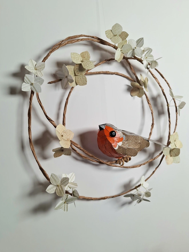 a robin red breast sculpture, sat on a flower wreath, art for the wall