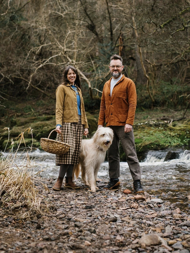 Man and woman in the woods with lurcher dog standing between them