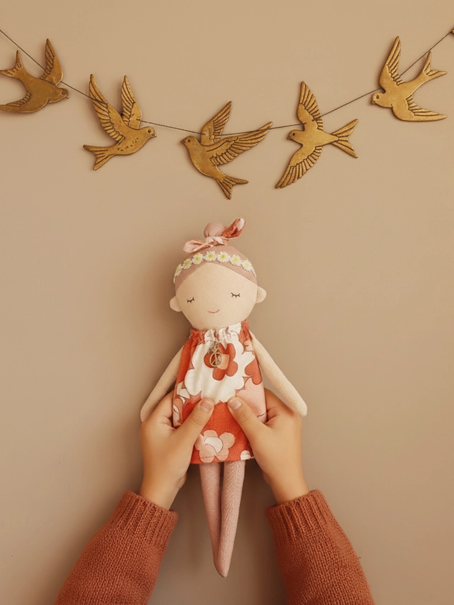 Handmade fabric doll called Peace Wishing Flower Child Doll, wearing peach and white retro floral dresses, daisy headbands, and bow topknots. It has serene embroidered face, peace sign charm around its neck