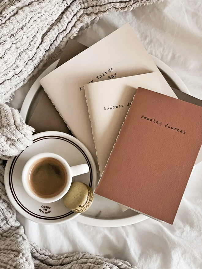 fan of journals laid on top of one another, beside an espresso
