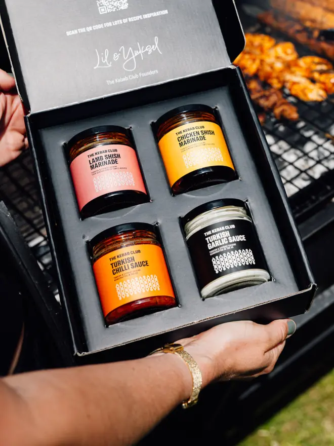 Open gift box of the Signature Kebab Sauce Gift Box held open in front of a barbecue in an outdoor setting
