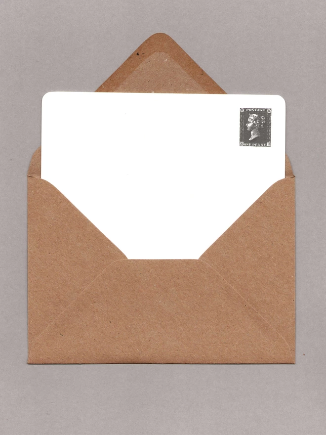 White notecard with a black penny black stamp at the top-right corner inside an open kraft envelope