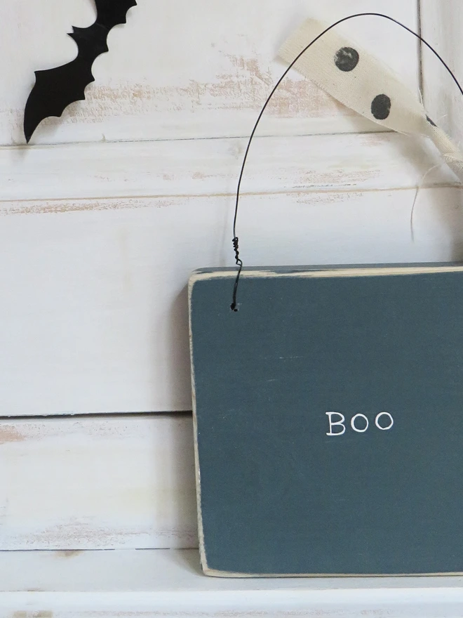 inky blue hand painted wooden sign with boo message and spotty ribbon detail