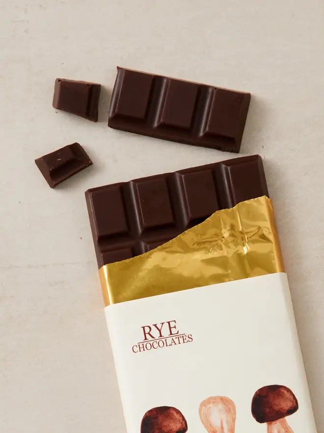 lions mane dark chocolate. a bar of chocolate in wrapping featuring illustrate mushrooms.