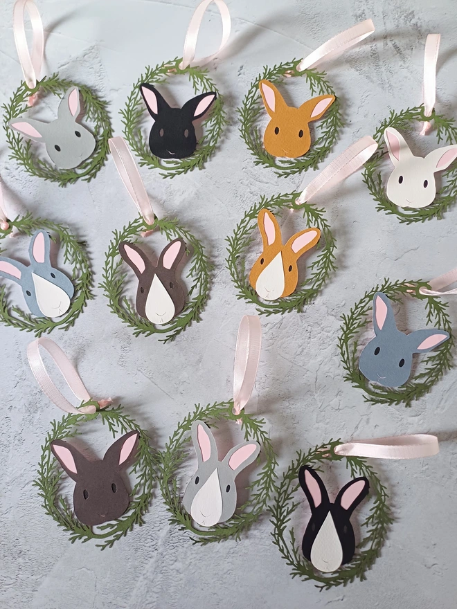 Entire Range of Easter Tree Bunny Decorations laid flat on grey surface. Each decoration is threaded with a pale pink ribbon hanging loop